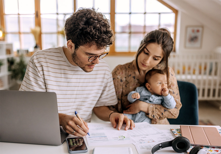 Man and woman holding baby looking at papers with numbers on them